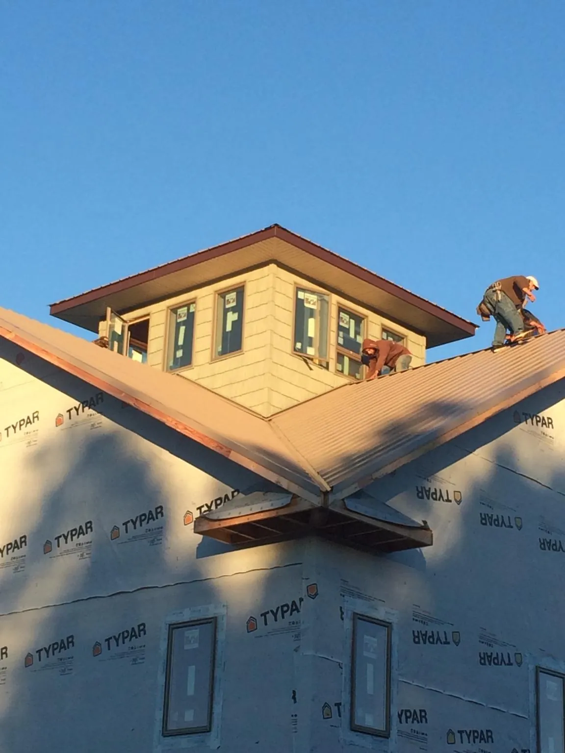 Roofers working around a rooftop cupola on a new metal roof at sunset — Roof Waterproofing in Plymouth by Roofing Brothers